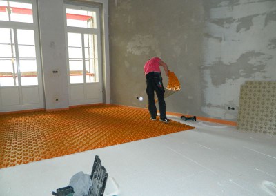 Handwerker beim Verlegen  des Montageunterbaus für die Fußbodenheizung